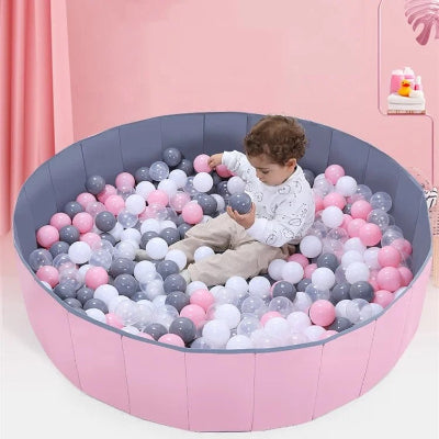 Bébé scrulpte minutieusement les balles et les couleurs de sa piscine a balle pour bebe.