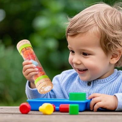 Le bébé content, souriant lorsqu'il commence à comprendre la relation de cause à effet grace à son baton de pluie.