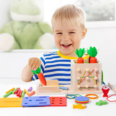 Tout souriant, le tout petit fait correspondre les objets du cube de motricité aux formes