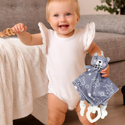 un bébé tout joyeux avec son doudou ours dans sa main gauche.