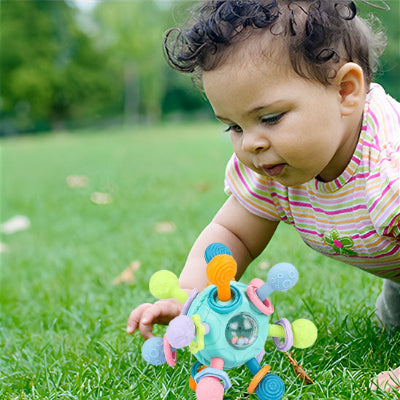 Bébé en plein séance d'éveil avec son hochet dans le jardin