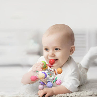 Visage relaxé et joyeux avec une cone de son hochet bebe entre sa dentition