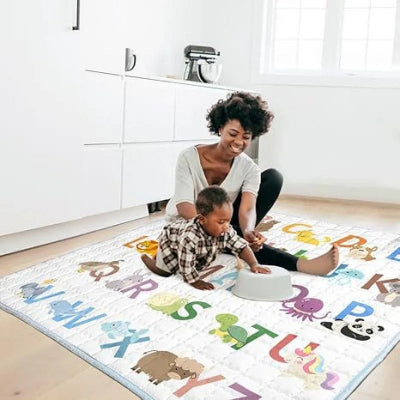 Maman aide le bébé à jouer au jeu imaginatif d'attrape poisson sur la mousse tapis bebe.