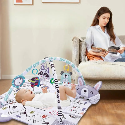 Maman fait une pause lecture au calme pendant que bébé gazouille face aux jouets suspendus du tapis d'éveil bébé