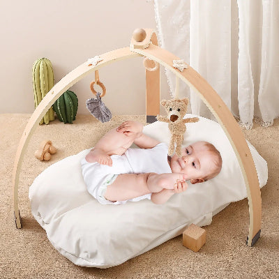 Regard fixe sur les pendentifs de l'arche bebe bois, le tout petit essai de les atteindre des pieds.