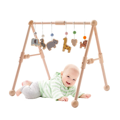 Bébé en plein effort pour atteindre les pendentifs sur son arche d'éveil