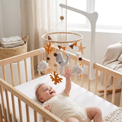 Bébé essaye d'attrapper le dauphin du mobile bebe
