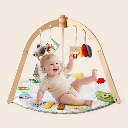 Bébé tire sur les suspendus du tapis d'éveil bébé tout en maintenant le pied en l'air 