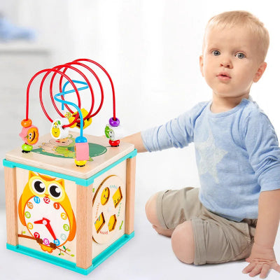 Le tout petit absorbé à actioner le mouvement des engrenades de son cube motricité bébé