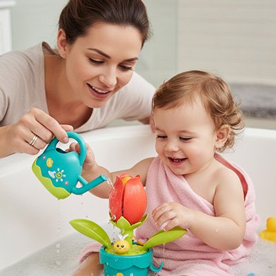 Maman guide ses petites mains pour arroser la fleur de son jouet bebe bain