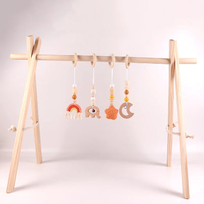 Jouet pour arche d'éveil orange sur un arche bebe dans un décor boisé 