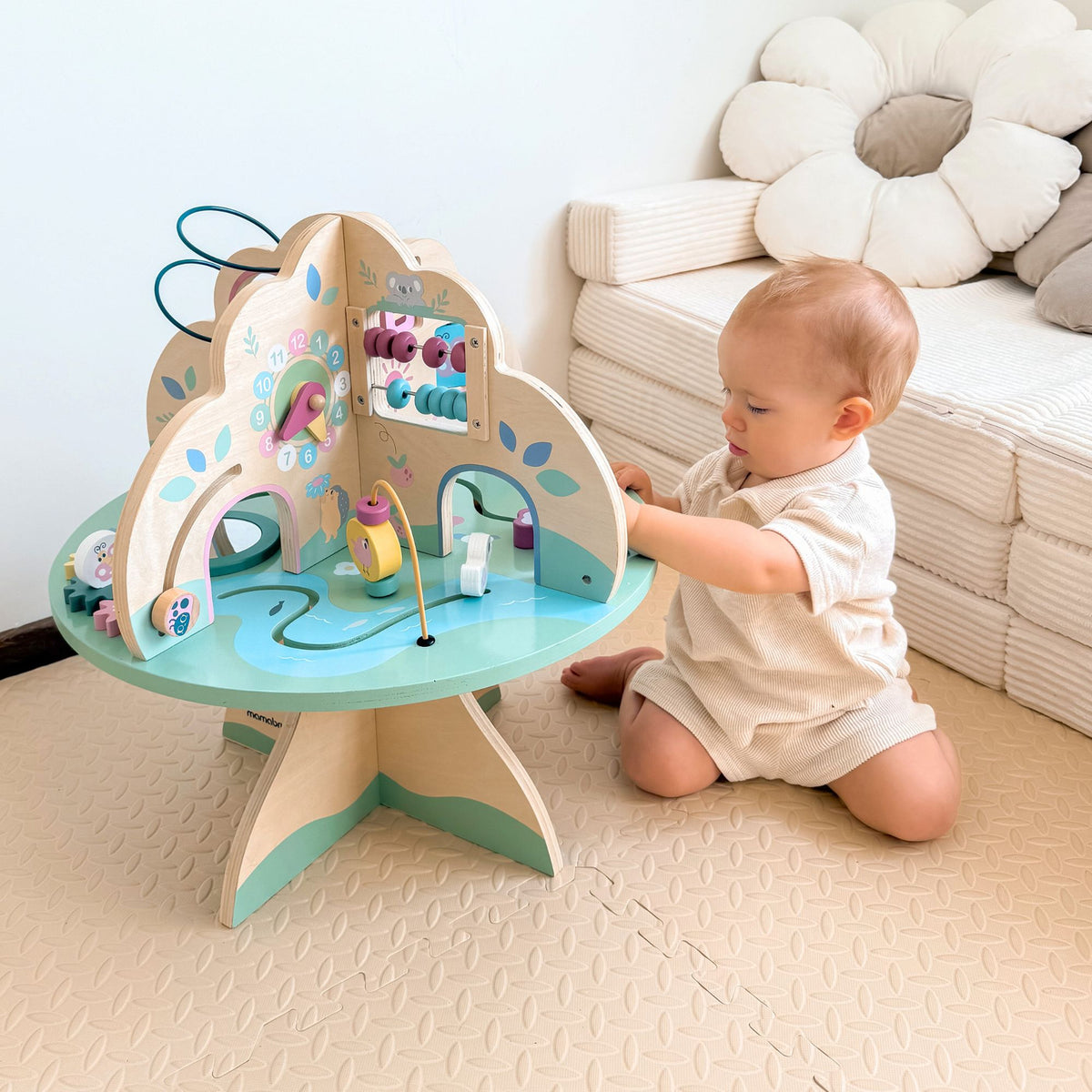 Bébé manipule  son cube de motricité assis sur ses genoux 