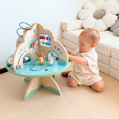 Bébé manipule  son cube de motricité assis sur ses genoux 