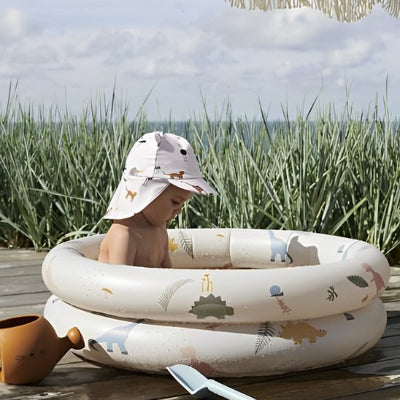 La petite profite de sa piscine gonflable en plein été dans le coin du jardin