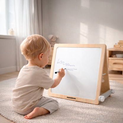 Bébé essaye de faire des traits sur le tableau du cube de motricité bébé 