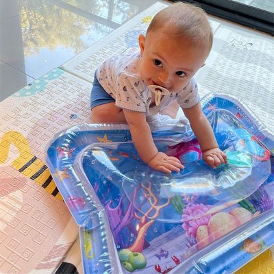 Bébé essaie de jouer avec l'eau contenu dans son tapis d'eau à ain nues 