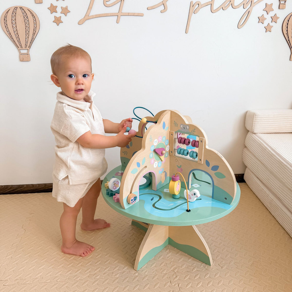 Bébé debout, tire et tourne les perles de son cube de motricité 